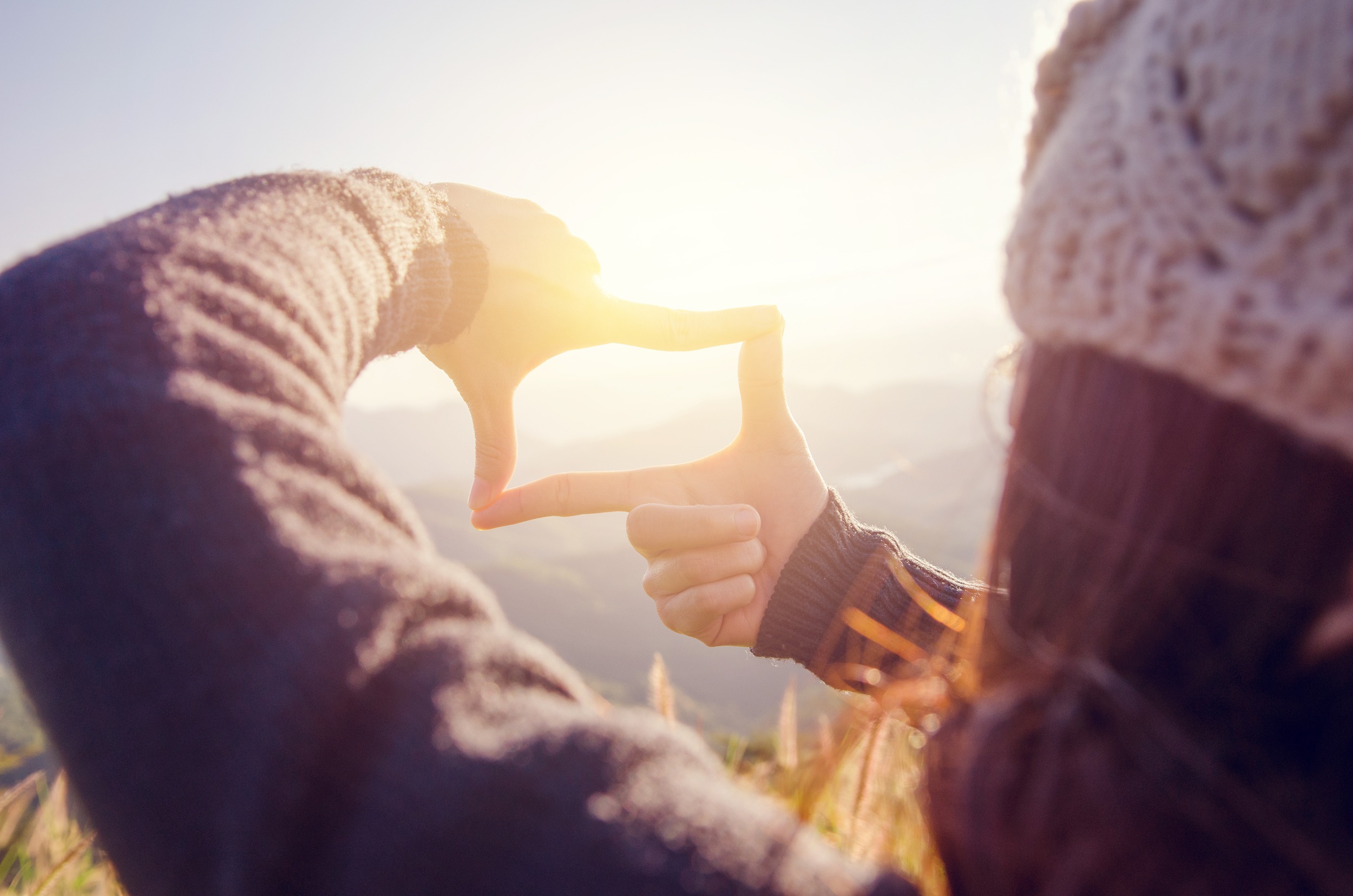 Close up of woman hands making frame gesture with sunrise on moutain,